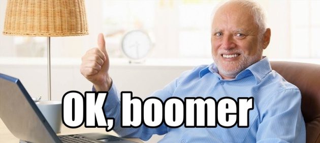 Un uomo coi capelli bianchi e un sorriso costretto fa il segno OK con il pollice davanti a un laptop. Davanti a lui campeggia la scritta "OK, boomer"